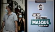 A man and a woman wearing protective face masks due to the COVID-19 coronavirus pandemic, walk past a mandatory wearing mask sign, in Bordeaux, southwestern France, on July 18, 2020. / AFP / Philippe LOPEZ