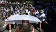 A woman holds an umbrella to protect herself from the sun as protesters respect social distancing measures during a demonstration by independence supporters in Santiago de Compostela on July 25, 2020. / AFP / MIGUEL RIOPA