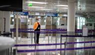 (FILES) In this file photo taken on May 14, 2020 a member of Charles de Gaulle airport personnel wears a protective face mask in the deserted passport control section of arrivals in Terminal 2 of Charles de Gaulle international airport in Roissy near Pari