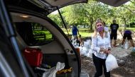 Palmetto Bay's Mayor Karyn Cunningham, puts sandbags in a resident's car trunk in Palmetto Bay near Miami, on July 31, 2020 as Floridians prepare for Hurricane Isaias while a State of Emergency has been declared for 19 Counties. AFP / CHANDAN KHANNA

