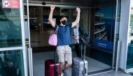 A traveller, mask-clad due to the COVID-19 coronavirus pandemic, arriving on one of the first flights from Britain gestures as he walks with luggage out of the terminal at Cyprus' Larnaca International Airport on August 1, 2020. / AFP / Iakovos Hatzistavr