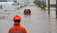 In a photo taken on August 3, 2020 rescue services help people cross a flooded field in a village near Cheonan, following heavy rain. Damage from heavy rain that pounded the country's central region earlier this week continued to grow, leaving 13 dead and