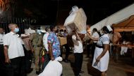 A health official takes the temperature of election officials who arrive with ballot boxes from a polling station to a counting center, after the voting ended during the country's parliamentary election in Colombo, Sri Lanka, August 5, 2020. REUTERS/Dinuk