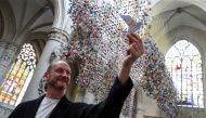 Belgian designer and artist Charles Kaisin poses next to an art installation made of 20,325 origamis called 