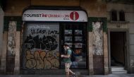 A man walks past a closed tourist office in the centre of Barcelona on August 12, 2020. / AFP / Josep LAGO