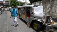 In this photo taken on August 12, 2020, a resident walks past jeepneys serving as temporary homes parked along a road in Manila. FOCUS by Ron LOPEZ / AFP / Ted ALJIBE 