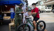 A police officer checks a bicycle rider's quarantine pass at a checkpoint placed amid the reimposed strict lockdown to curb coronavirus disease (COVID-19) infections, in Manila, Philippines, August 17, 2020. REUTERS/Eloisa Lopez