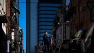 A man wearing a facemask walks in the outskirts of Madrid on August 19, 2020, with the Cuatro Torres bussiness area in the background. / AFP / OSCAR DEL POZO