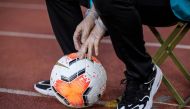 This file photo taken on July 25, 2020 shows a staff member wearing a pair of protective gloves holding a ball during the Chinese Super League (CSL) football match between Guangzhou Evergrande and Shanghai Shenhua in Dalian in China's northeastern Liaonin