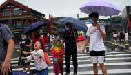 People wearing face masks walk near Qianmen Street on a rainy day, following the coronavirus disease (COVID-19) outbreak, in Beijing, China August 18, 2020. REUTERS/Tingshu Wang
