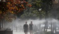 People walk through a water sprinkler on a hot summer day in central Kyiv, Ukraine August 21, 2020. REUTERS/Gleb Garanich