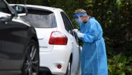 A medical worker wearing a protective suit and a mask takes a swab sample for a coronavirus disease (COVID-19) test at a drive-through testing station in Salo, Finland August 18, 2020. Lehtikuva/Jussi Nukari via REUTERS