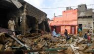 Residents sit over the debris of their collapsed houses at a flooded residential area after heavy monsoon rains in Pakistan's port city of Karachi on August 26, 2020. Heavy monsoon rains have also wrought havoc on neighbouring Pakistan, with authorities i