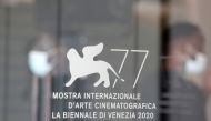 Workers wearing protective face masks are seen through the doors of Palazzo del Casino, ahead of the 77th Venice Film Festival, the first major international film festival held since the coronavirus disease (COVID-19) outbreak, in Venice, Italy, September
