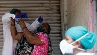 A woman reacts as a health worker in personal protective equipment (PPE) takes a swab during a check-up campaign for the coronavirus disease (COVID-19) in a slum area in Mumbai, India September 5, 2020. REUTERS/Francis Mascarenhas