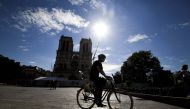 :A man rides his bicycle by Notre-Dame cathedral, on September 4, 2020, in Paris. / AFP / ALAIN JOCARD
