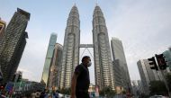 FILE PHOTO: A man wearing a protective mask crosses a street in front of Petronas Twin Towers, amid the coronavirus disease (COVID-19) outbreak in Kuala Lumpur, Malaysia August 11, 2020. REUTERS/Lim Huey Teng