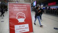 People wearing protective face masks pass a sign at Waterloo station during the morning rush hour, amid the coronavirus disease (COVID-19) outbreak, in London, Britain, September 23, 2020. REUTERS/Hannah McKay