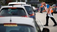 An NHS track and trace worker talks with people as they arrive at a drive in test centre following the outbreak of the coronavirus disease (COVID-19) in Bolton, Britain, September 22, 2020. REUTERS/Phil Noble