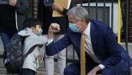 (FILES) In this file photo New York City Mayor Bill de Blasio does a social distancing elbow bump with four-year old Oliver as he welcomes students to Pre-K at Mosaic Pre-K Center in the Queens section of New York September 21, 2020. AFP / TIMOTHY A. CLAR