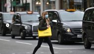 A woman wearing a protective face covering passes parked taxi cabs as she crosses Oxford Street in London, on October 17, 2020, as Londoners face more stringent novel coronavirus COVID-19 restrictions as the number of cases rises. AFP / JUSTIN TALLIS
