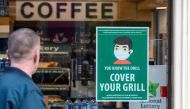 An information poster advising the wearing of face coverings as a precaution against the spread of the novel coronavirus covid-19 is seen on the window of a coffee shop in Dublin on October 21, 2020 as Ireland prepares to enter a second national lockdown 