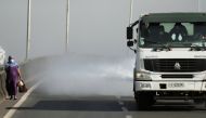 FILE PHOTO: A woman wearing a face mask walks next to a truck spraying disinfectant on the street as part of measures to prevent the potential spread of coronavirus (COVID-19), in Addis Ababa, Ethiopia March 29, 2020. REUTERS/Tiksa Negeri/File Photo
