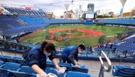 Workers take cleaning seats of the Yokohama Stadium, which will host baseball and softball games during the Tokyo Olympics, prior to a professional baseball game in Yokohama, Kanagawa prefecture on October 30, 2020. / AFP / Kazuhiro NOGI
