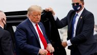FILE PHOTO: U.S. President Donald Trump holds a 'Make America Great Again' cap while arriving to board Air Force One as he departs Florida for campaign travel to North Carolina, Pennsylvania, Michigan and Wisconsin at Miami International Airport in Miami,