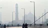 Motorcyclists ride on a bridge amid heavy smoggy conditions in Lahore on November 10, 2020. / AFP / Arif ALI
