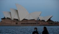 People stand on the harbour waterfront near the Sydney Opera House in Sydney, Australia, November 11, 2020. REUTERS/Loren Elliott/File Photo