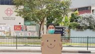 Jolovan Wham wears a mask and holds a cardboard with a drawing of a smiley face in Singapore, March 28, 2020. Picture taken March 28, 2020. Jolovan Wham/Handout via REUTERS 