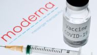 This picture taken on November 18, 2020 shows a syringe and a bottle reading 