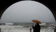 A man shelters under an umbrella from heavy rains while looking out to the Indian ocean as Cyclone Nivar approaches the southeastern Indian coast in Puducherry on November 25, 2020. Several thousand people in south-eastern India fled their homes on Novemb