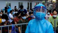 A healthcare worker wearing protective suit walks past as local residents, who have returned after travelling to Da Nang, wait at a coronavirus disease (COVID-19) testing center in Hanoi, Vietnam August 10, 2020. REUTERS/Kham/File Photo