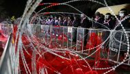Riot police officers stand guard behind barb wires covered with red paint during a pro-democracy rally demanding Prime Minister Prayuth Chan-ocha to resign and reforms to the monarchy, at 11th Infantry Regiment, in Bangkok, Thailand, November 29, 2020. Re