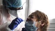 (Files) This file photo taken on May 13, 2020, shows a member of the Covisan program testing a member of a family confined at home as they reported a suspected case of Covid-19, in Gennevilliers near Paris. AFP / Alain Jocard 