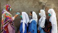 Students wear protective face masks as they have their temperature checked before entering a class, after the government allowed the reopening of schools from grade six to eight amid the coronavirus disease (COVID-19) pandemic, in Peshawar, Pakistan Septe