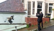 A man takes pictures of a new street artwork entitled 'Aachoo!!' by Banksy in Totterdown, Bristol, Britain December 11, 2020. REUTERS/Rebecca Naden