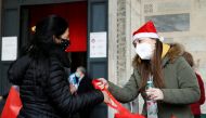 A woman receives a meal from a member of Rome-based charity Sant'Egidio Community in the church of Santa Maria in Trastevere, in Rome, Italy, December 25, 2020. (REUTERS/Yara Nardi)
