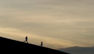 The silhouettes of two people jogging in the Phoenix Park, as the spread of the coronavirus disease (COVID-19) continues, in Dublin, Ireland, March 24, 2020. REUTERS/Jason Cairnduff/File Photo