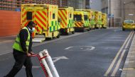 A worker pushes a trolley with the oxygen cylinders as ambulances queue at the Royal London Hospital amidst the spread of the coronavirus disease (COVID-19) pandemic, in London, Britain, January 9, 2021. REUTERS/Simon Dawson
