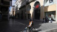 A child rides a bike past a closed shop, amid lockdown restrictions due to the spread of the coronavirus disease (COVID-19) pandemic, in Athens, Greece, February 6, 2021. REUTERS/Costas Baltas