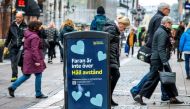 FILE PHOTO: People walk near a trash can with a sign reading 