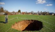 Man is seen next to sinkhole is seen in village Mecencani, Croatia, February 12, 2021. Picture is taken February 12, 2021. REUTERS/Antonio Bronic
