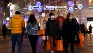 FILE PHOTO: People wearing protective face masks walk along a shopping street as the government prepares to bring in further restrictions over the Christmas period to curb the spread of the coronavirus disease (COVID-19) in Milan, Italy, December 18, 2020