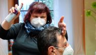 Hairdresser Manuela Friedl serves a customer as her salon reopens after a months-long lockdown, amid the coronavirus disease (COVID-19) pandemic in Haselbachtal, Germany, March 1, 2021. REUTERS/Matthias Rietschel