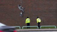 Police officers look at the mural of artist Banksy on a wall at HM Reading Prison in Reading, Britain in this picture obtained from the artist's official Instagram account. @banksy/banksy.co.uk via REUTERS