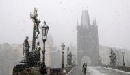 A woman walks across the medieval Charles Bridge during snowfall amid the coronavirus disease (COVID-19) outbreak in PRAGUE, Czech Republic, April 6, 2021. REUTERS/David W Cerny
