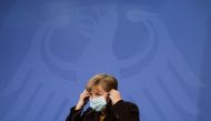 German Chancellor Angela Merkel puts on her face mask as she briefed the media after a virtual meeting with federal state governors at the chancellery in Berlin, Germany, March 30, 2021. Markus Schreiber/Pool via REUTERS/File Photo